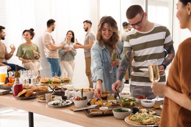 Bir grup insan açık büfenin tadını içeride birlikte çıkarıyor.