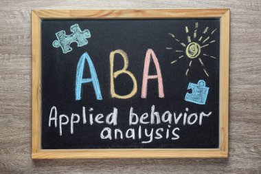 ABA yazılı küçük karatahta. Uygulamalı davranış analizi ve çizimler ahşap masa üzerinde, üst görünüm