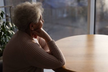 Yağmurlu bir günde pencereden dışarı bakan yaşlı bir kadın, mesaj için yer var. Yalnızlık kavramı