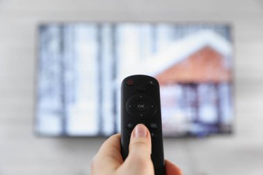 Uzaktan kumandalı bir kadın evde televizyon seyrediyor.