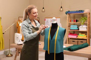 Atölyede iğne yastıklı bir terzi elbise yapıyor.