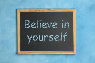 Motivasyon amaçlı alıntıları olan küçük yazı tahtası Açık mavi arka planda kendinize inanın, üst görünümde
