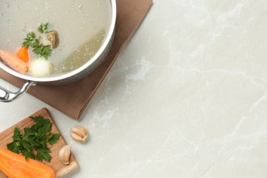 Lezzetli kemik suyu ve açık gri masadaki malzemelerle dolu tencere. Metin için boşluk
