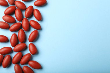 Açık mavi arka planda kırmızı haplar, düz yerde uzanıyordu. Anemi tedavisi