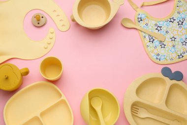 Pembe arka planda bebek beslenme aksesuarları ve önlüğü, düz yatış. Metin için boşluk