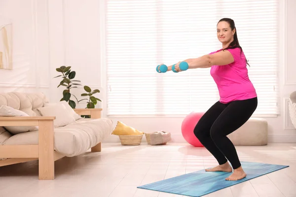 太りすぎの女性は家でダンベルで運動をします テキストのためのスペース — ストック写真