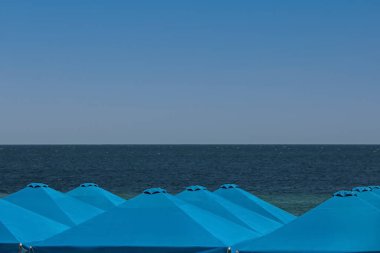 Güneşli bir günde tatil köyünde birçok plaj şemsiyesi