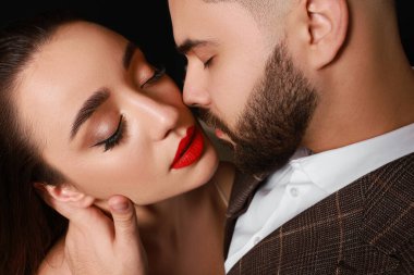 Siyah arka planda seksi bayan olan yakışıklı sakallı adam, yakın plan.