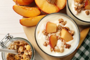 Taze şeftalili lezzetli yoğurt ve beyaz masada tahıl gevreği.