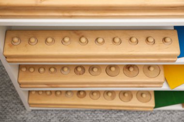 Odanın üstünde farklı ahşap geometrik bulmacaları olan raf ünitesi. Montessori oyuncağı