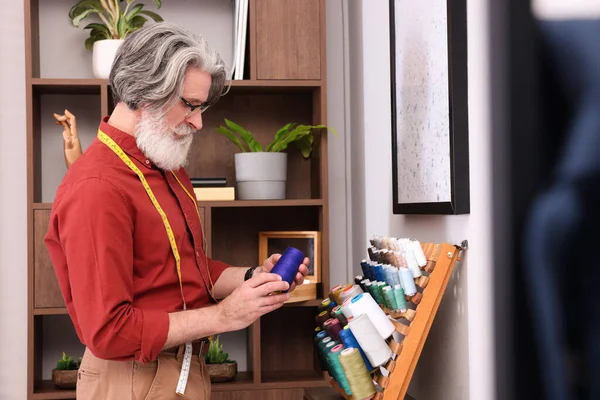 Atölyenin yanında iplik seçen profesyonel bir terzi