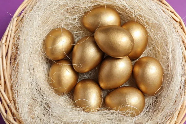 Glanzende Gouden Eieren Nest Violette Achtergrond Bovenaanzicht — Stockfoto