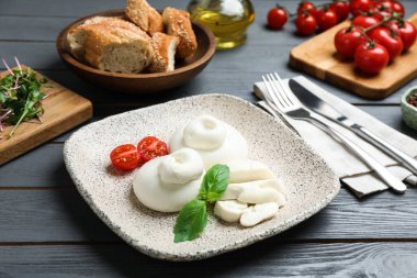 Gri ahşap masada servis edilen lezzetli burrata peyniri.