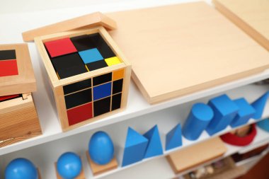 Raflardaki tahta geometrik nesneler ve diğer montessori oyuncakları.