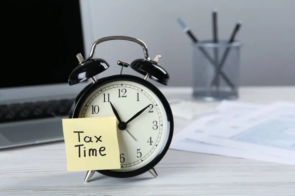 闹钟和提醒字条在白色木制桌子上注明纳税时间 案文的篇幅 — 图库照片