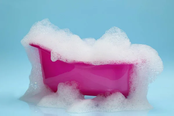 明るい青の背景に泡が溢れるおもちゃの浴槽 — ストック写真