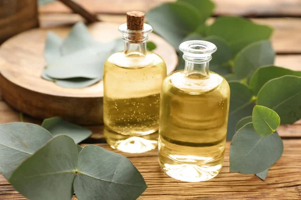 Okaliptüs şişeleri ahşap masa üzerinde gerekli yağ ve bitki dalları