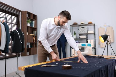 Atölyede çalışan mezuralı bir terzi.