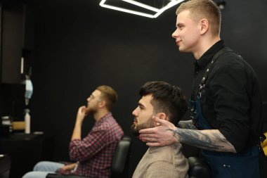 Berber dükkanında sakallı müşteriyle çalışan profesyonel bir kuaför.