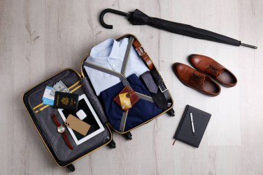 Tahta yüzeyde iş gezisi eşyalarıyla dolu bavul, düz yatıyordu.