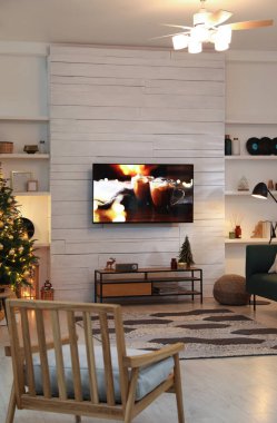Beyaz ahşap duvardaki plazma TV oturma odasında Noel için güzelce dekore edilmiş.