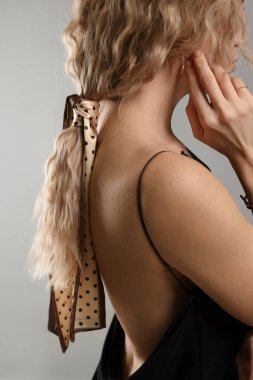 Açık gri arka planda şık bandanalı kadın, yakın plan.