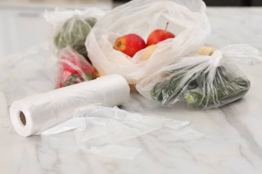 Beyaz mermer masada farklı taze ürünlerin olduğu plastik torbalar.