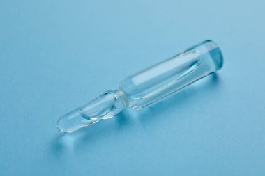 Açık mavi arkaplanda enjeksiyon için çözünürlüğe sahip tıbbi ampul