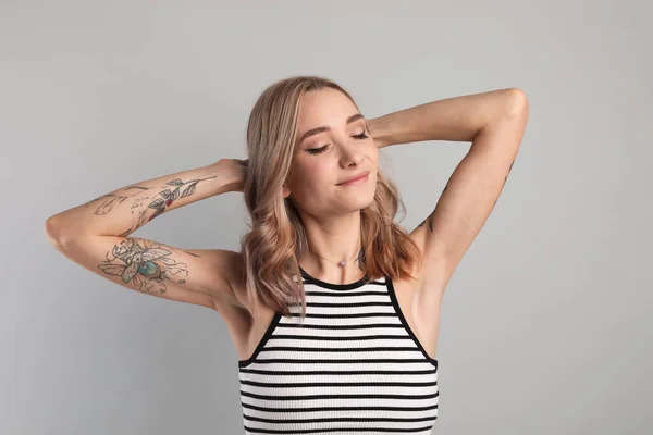 Mulher Bonita Com Tatuagens Nos Braços Contra Fundo Cinza — Fotografia de Stock