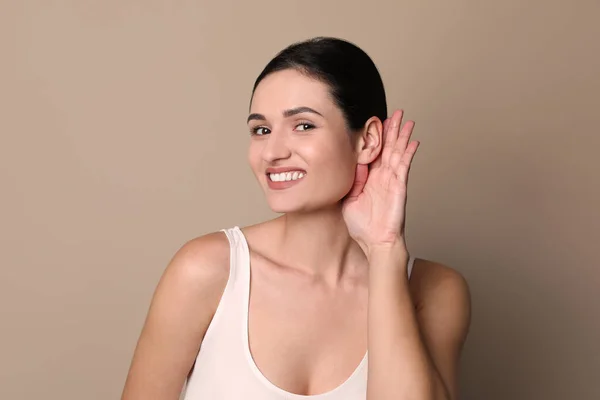 Mladá Žena Ukazující Gesto Ruky Uchu Šedém Pozadí — Stock fotografie