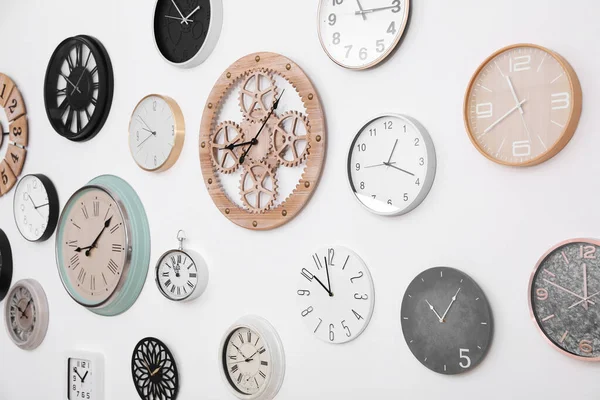 白い壁に掛けられた異なる時計のコレクション — ストック写真
