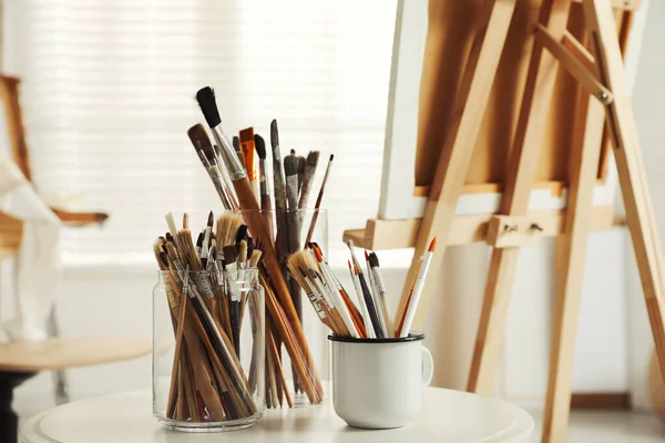 Stüdyodaki beyaz masada farklı boya fırçaları olan tutucular. Sanatçının işyeri
