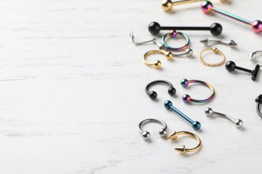 Beyaz ahşap masa üzerindeki piercing mücevherleri, metin için yer