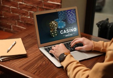 Ahşap masada dizüstü bilgisayarda poker oynayan adam, yakın plan. Kumarhane çevrimiçi
