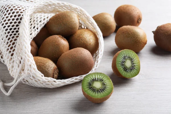 Bolsa Red Con Corte Kiwis Frescos Enteros Sobre Mesa Madera — Foto de Stock