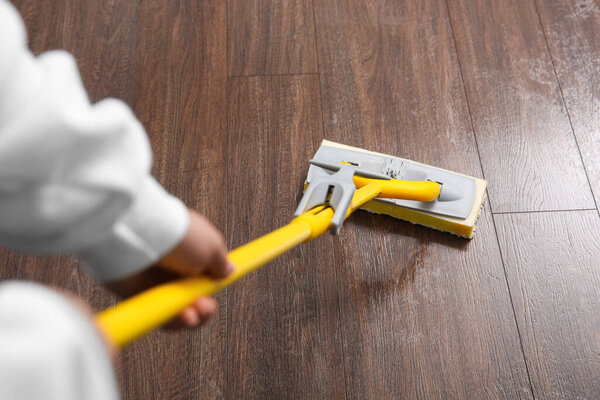 Woman cleaning parquet floor with mop, above view