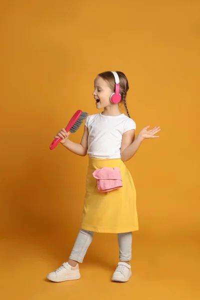 Cute Little Girl Słuchawki Szczotką Śpiew Pomarańczowym Tle — Zdjęcie stockowe