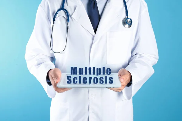 Multiple Sclerosis concept. Doctor holding modern tablet on turquoise background, closeup