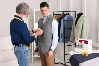 Atölyede müşteriyle çalışan profesyonel terzi