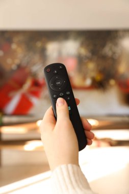 Uzaktan kumandalı bir kadın evde televizyon seyrediyor.
