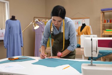 Atölyede terzi kumaşı tebeşirle işaretliyor