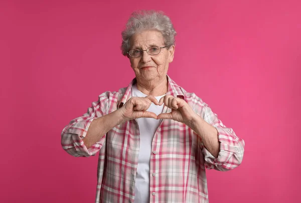 Elderly Woman Making Heart Her Hands Pink Background — 스톡 사진