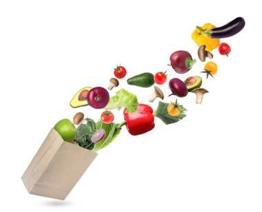 Beyaz arka planda farklı meyve ve sebzelerle dolu kese kağıdı.