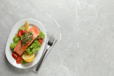 Pesto soslu, lezzetli somon balığı ve gri masada taze salata. Metin için boşluk