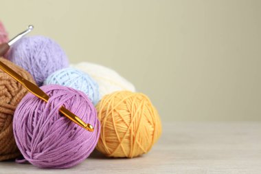 Renkli örgü iplikleri ve bej arka planda beyaz ahşap masaya örgü kancaları. Metin için boşluk