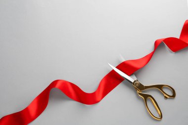 Red ribbon and scissors on light grey background, top view. Space for text clipart
