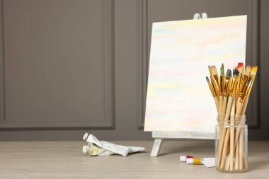 Farklı fırçalar, soyut resimli sehpa ve ahşap masa boyaları. Metin için boşluk