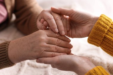 Genç ve yaşlı kadınların el ele tutuşması, yakın çekim.