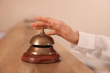 Ahşap resepsiyonda otelin servis zilini çalan kadın, yakın plan.
