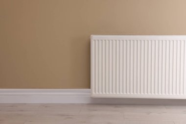 Bej duvarda modern radyatör, yazı için yer var. Merkezi ısıtma sistemi